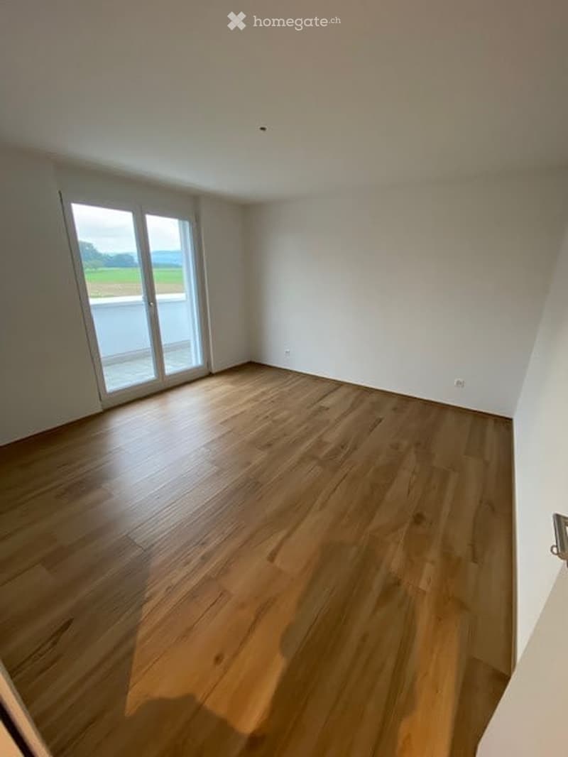 hardwood floor, sliding glass door leading to balcony, large windows, white walls
