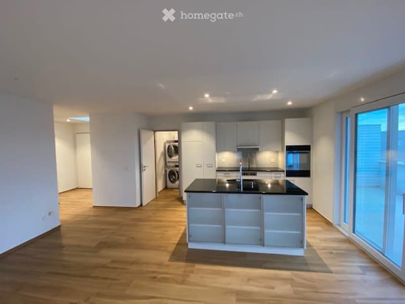 kitchen with island, built-in appliances, wooden floor, white cabinets, washing machine in room