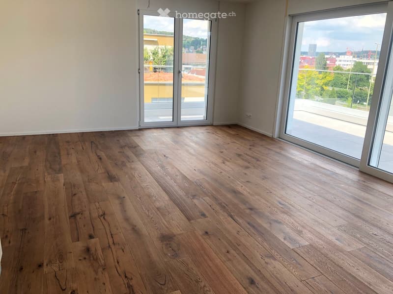 Empty room with wooden flooring and large glass sliding doors leading to a balcony.