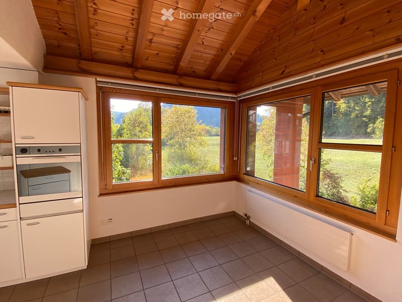 Bright kitchen with wooden ceiling, large windows offering a scenic view, and modern appliances including a cabinet, oven, and refrigerator.