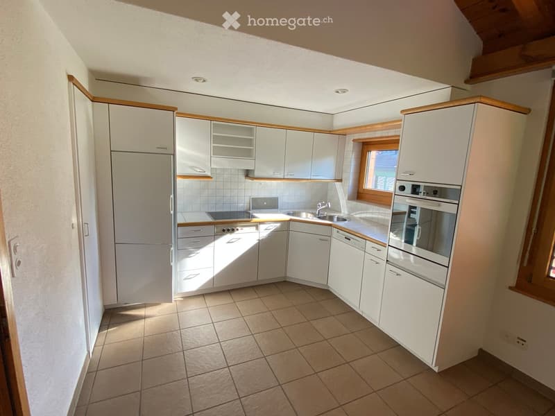 Modern kitchen with white cabinets, stainless steel appliances, tiled floor, and a window providing natural light.