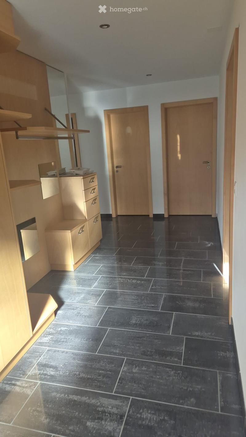 Empty hallway with dark tiled floor, light-colored walls, and two wooden doors.