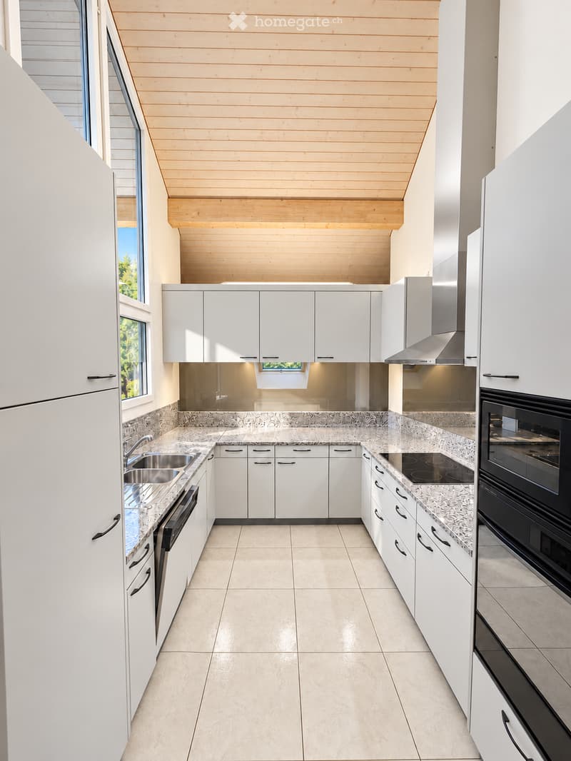 Modern kitchen with white cabinets, granite countertops, stainless steel appliances, and a skylight above the island.
