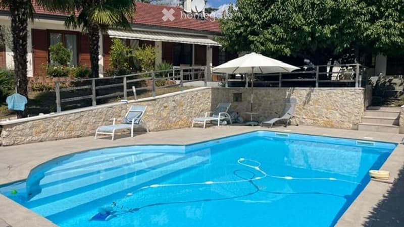 Private outdoor area with a swimming pool, lounge chairs, umbrella, and a small table.