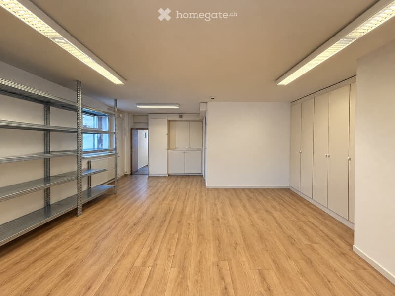 Empty room with wooden flooring, white walls, built-in cabinets, and metal shelving unit. No furniture or personal items present.