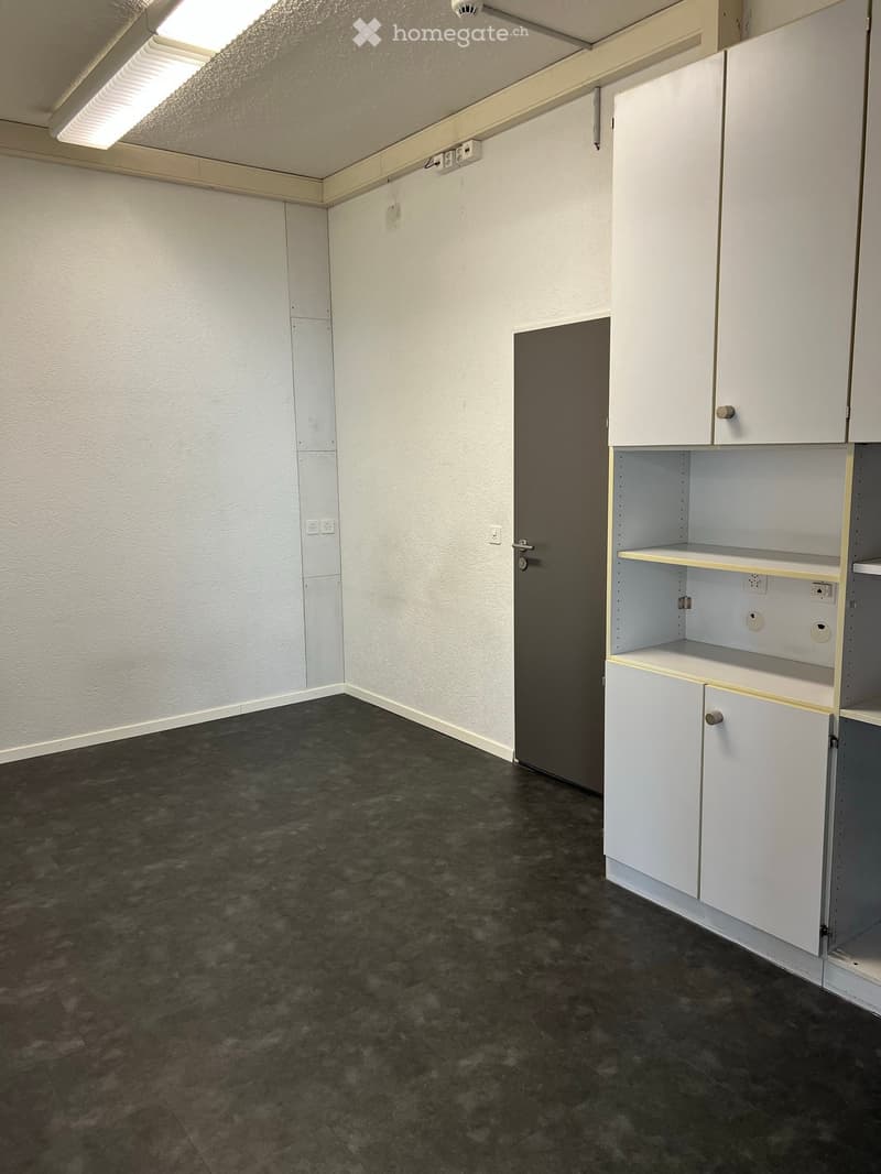 Empty room with white walls, dark tiled floor, white built-in cabinets, and a closed door.