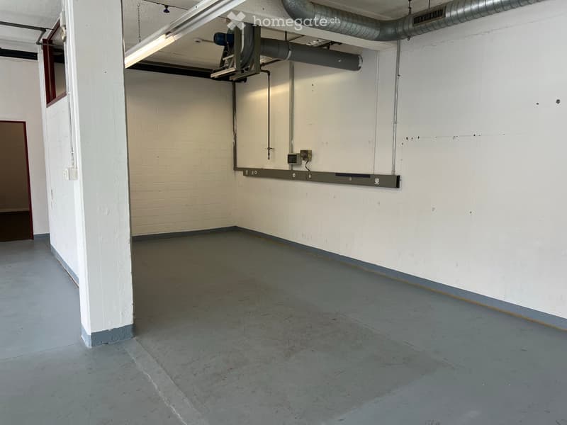 Empty room with concrete floor, white walls, and exposed pipes and electrical panels. No furniture or equipment present.