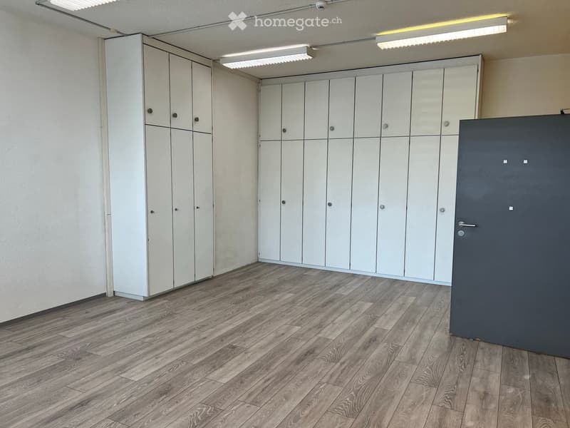 Empty room with light-colored wooden flooring and white built-in storage units along the walls.