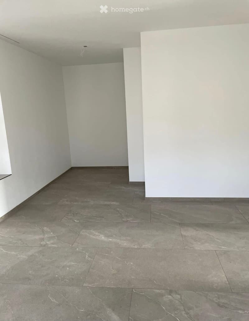 Empty room with light-colored walls and a polished marble tile floor. No furniture or equipment is present.