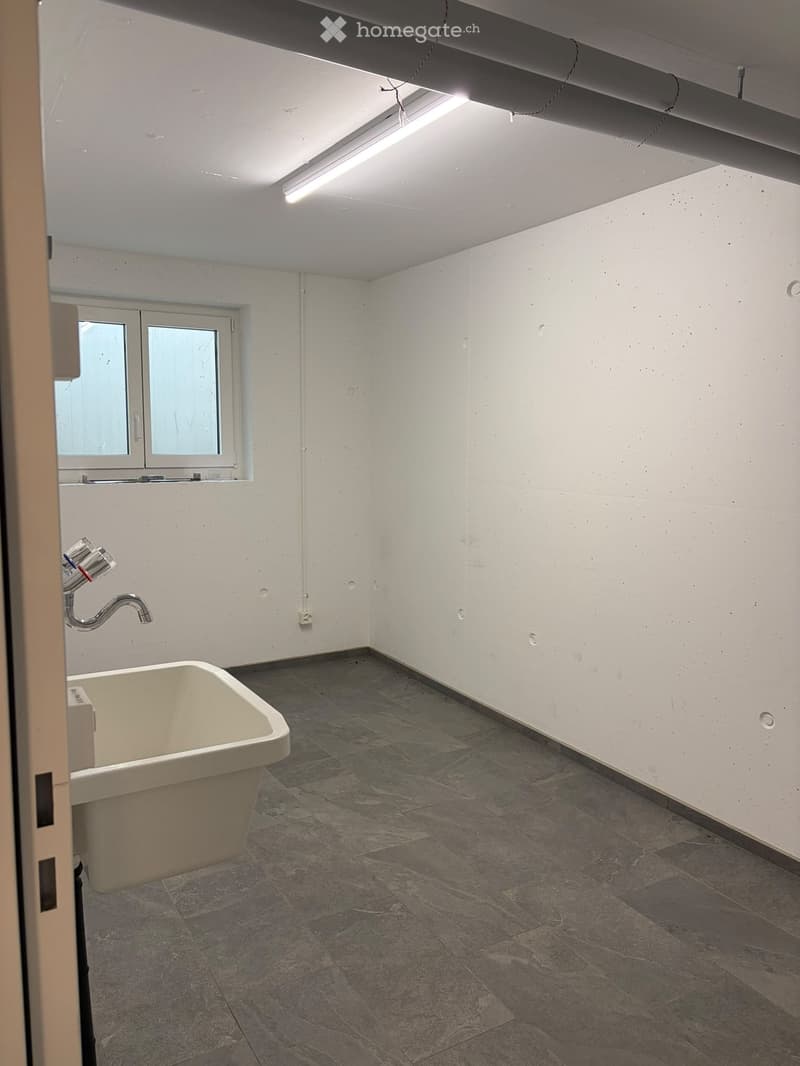 Empty bathroom with a bathtub, faucet, and a window. The walls are white, and the floor is tiled.