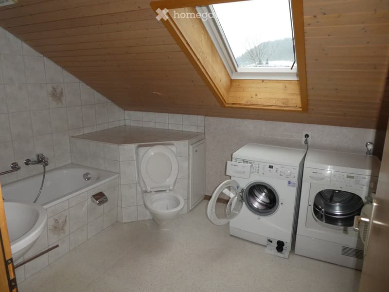 Bathroom with a bathtub, toilet, washing machine, and dryer, featuring a skylight window and wooden ceiling.