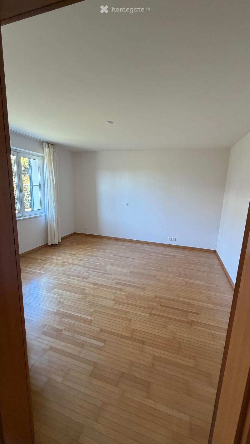 Empty room with light wooden flooring, white walls, and a window with a curtain. No furniture or equipment is present.