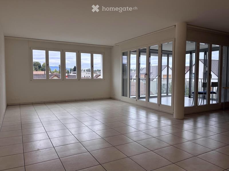 Empty room with tiled floor, large windows, and sliding glass doors leading to a balcony.
