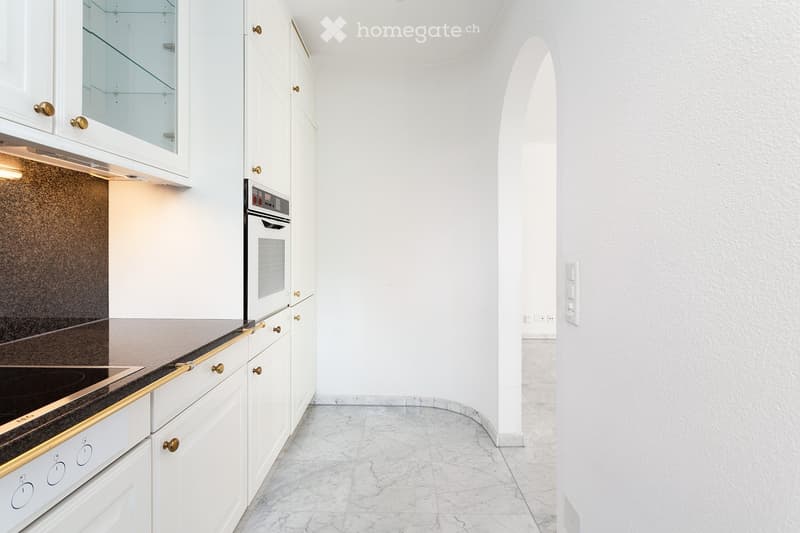 Modern kitchen with white cabinets, a built-in oven, and a marble floor. The space features sleek, contemporary design elements and ample storage.
