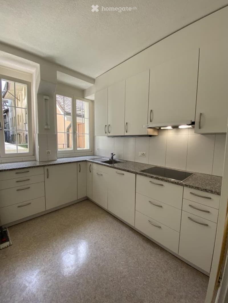 Modern kitchen with white cabinets, granite countertop, and stainless steel appliances.