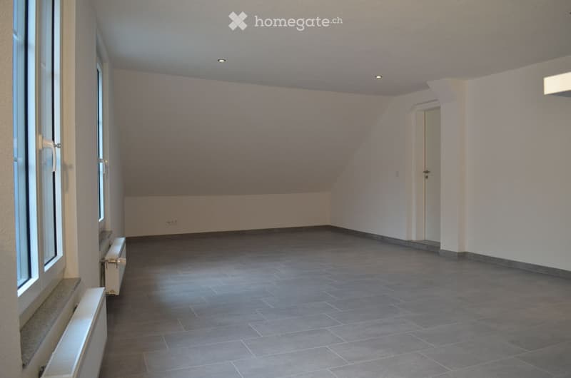 Empty room with grey tiled floor, white walls, and large windows. No furniture or equipment visible.