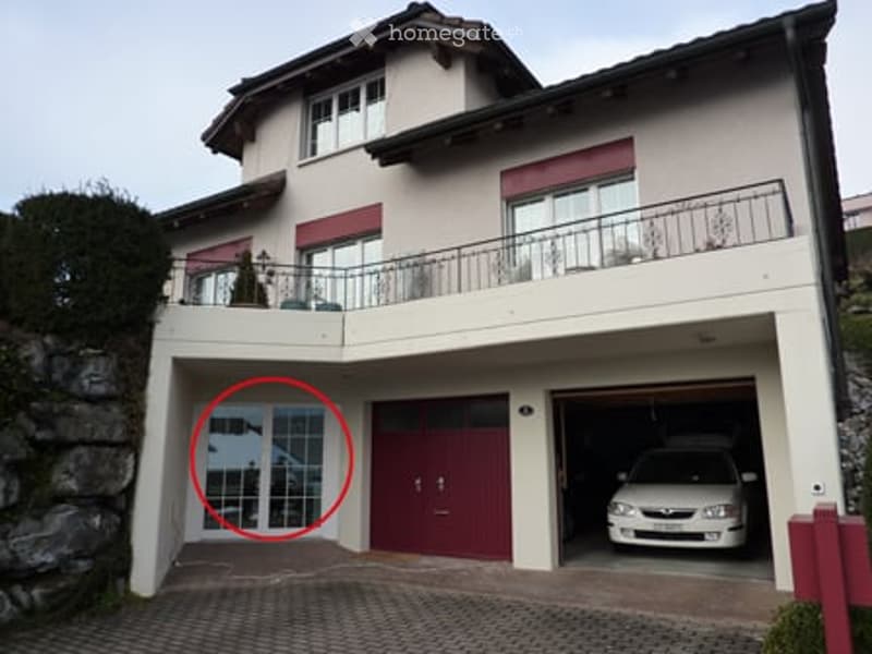 Two-story house with a garage, balcony, and a parked car in the driveway.