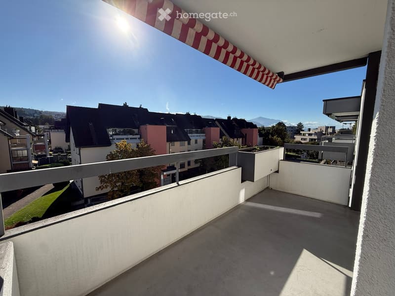 Balcony with metal railing, concrete floor, and a view of the surrounding neighborhood and mountains.