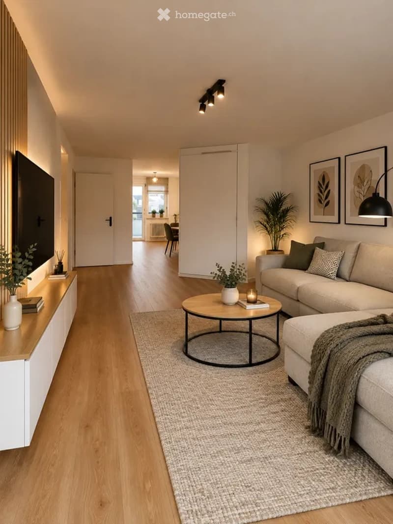 Modern living room with light wood flooring, a grey sofa, a round coffee table, a TV stand, and decorative plants.