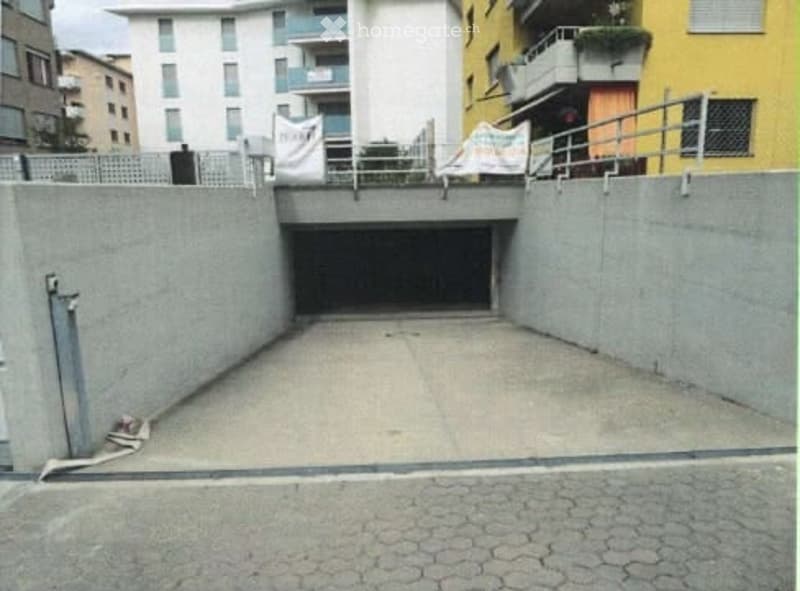 Underground garage with concrete walls and a single entrance ramp leading to the street.