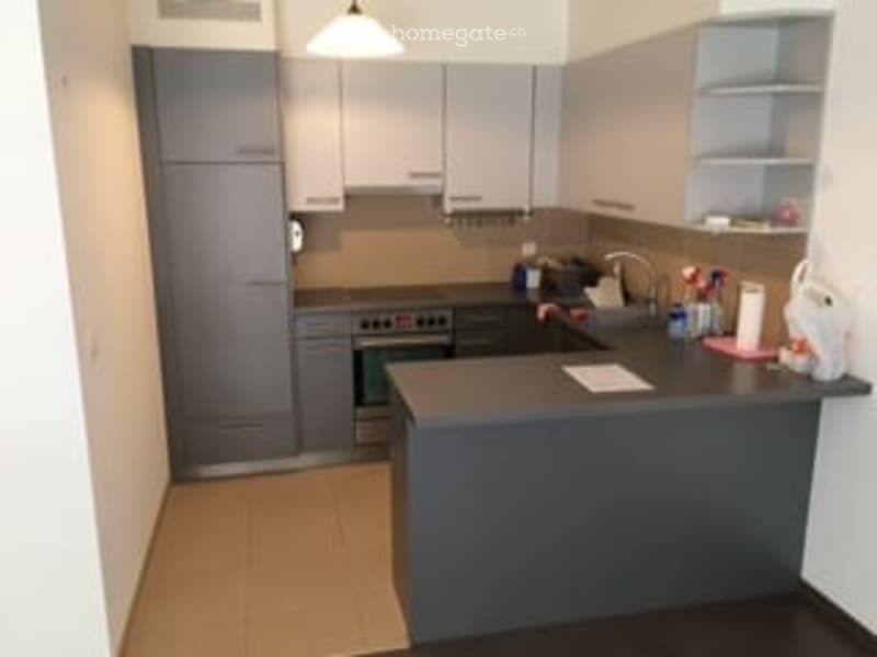 Modern kitchen with grey cabinets, a central island, and stainless steel appliances.