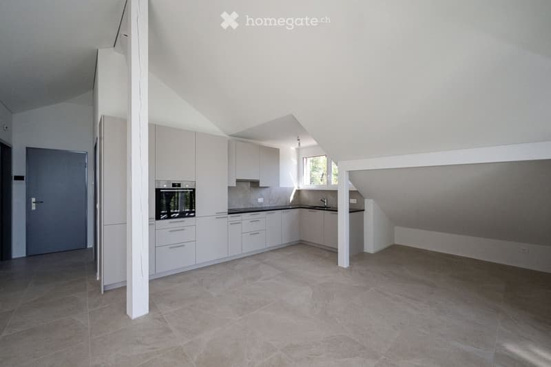 Modern kitchen with light-colored cabinets, an oven, and a sink, featuring tiled flooring and ample natural light from a window.