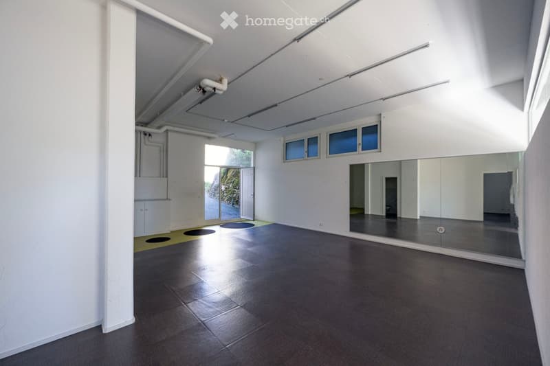 Empty room with white walls, dark tiled floor, large mirror, and a glass door leading to an outdoor area.
