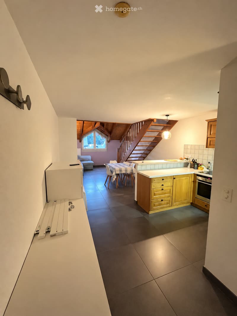 Open-plan kitchen and dining area with modern cabinets, a central island, and a staircase leading to an upper level.