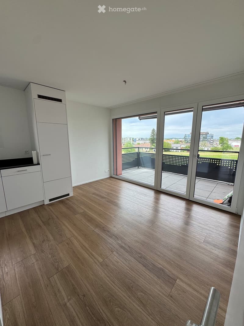 Empty room with wooden flooring, white cabinetry, and large sliding glass doors leading to a balcony with a view of the landscape.