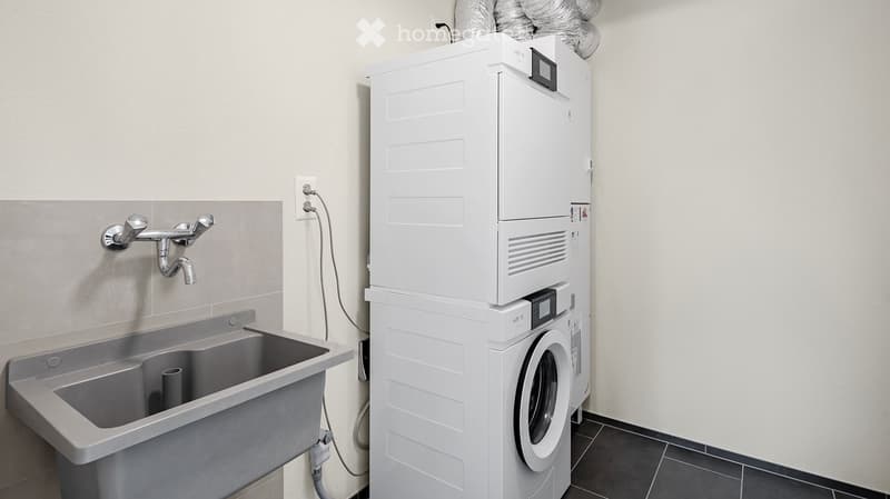 Bathroom with a sink, faucet, and stacked washing machine and dryer unit.