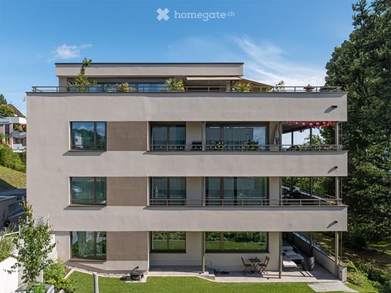 Modern three-story house with large windows, balconies, and a rooftop terrace overlooking a scenic valley.