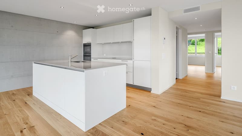 Modern kitchen with white cabinets, a central island, and a sink, featuring wooden flooring and recessed lighting.
