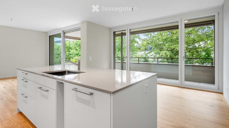 Modern kitchen with white cabinets, a central island, and large sliding glass doors leading to a balcony.