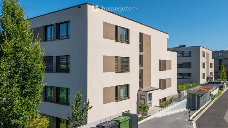 Modern multi-story residential building with large windows, beige facade, and numbered entrance.