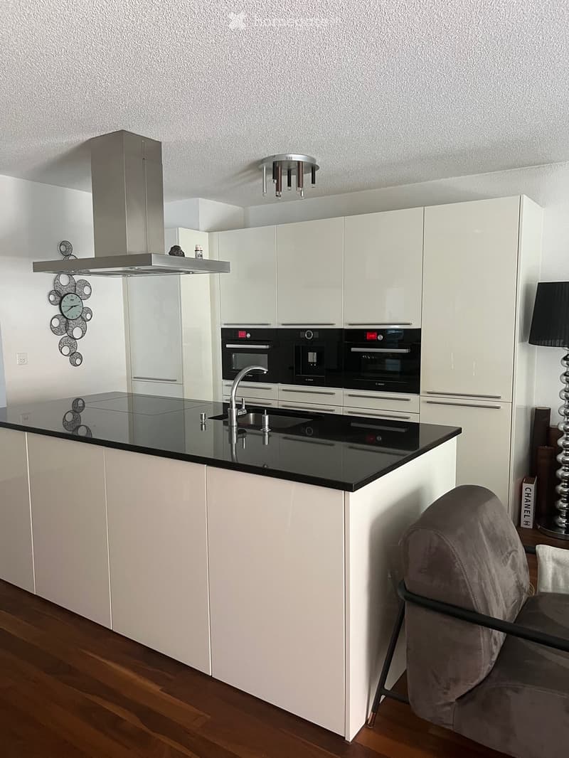 Modern kitchen with white cabinets, black countertop, stainless steel appliances, and a sleek design.