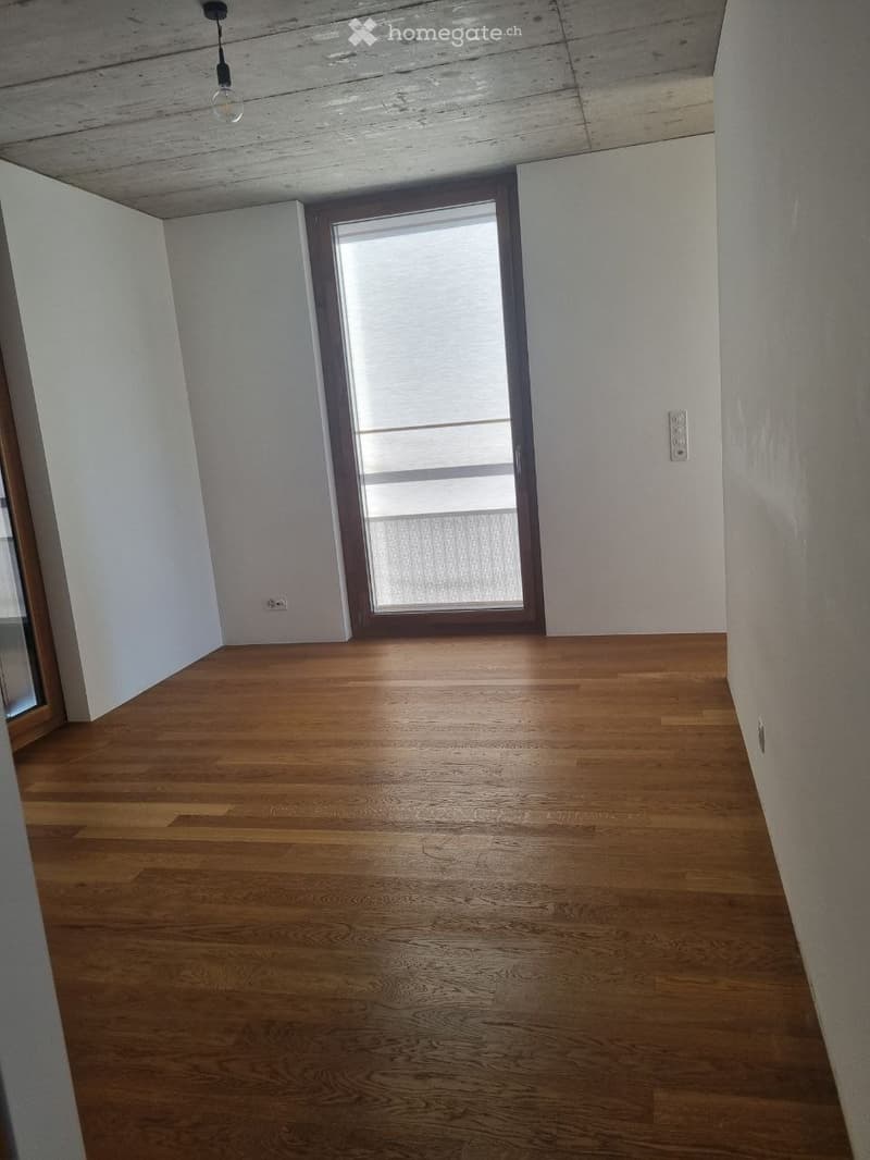 Empty room with wooden flooring, white walls, and a large window with blinds. No furniture or equipment is present.