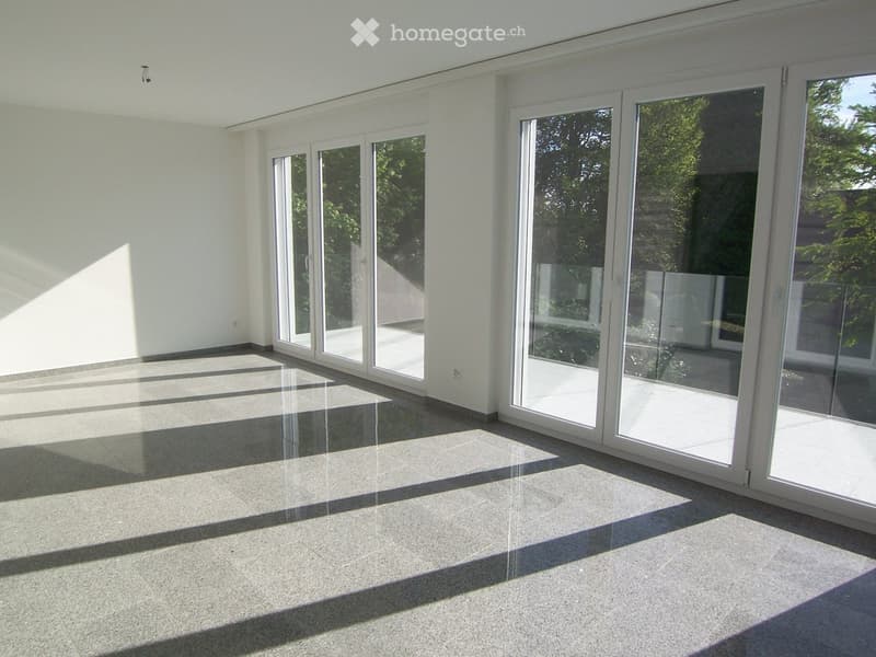 Empty room with large sliding glass doors, polished concrete floor, and white walls.