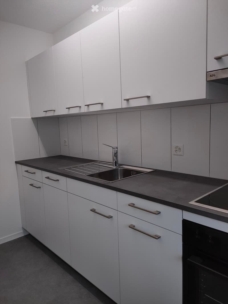 Modern kitchen with white cabinets, dark countertops, and stainless steel sink and oven.