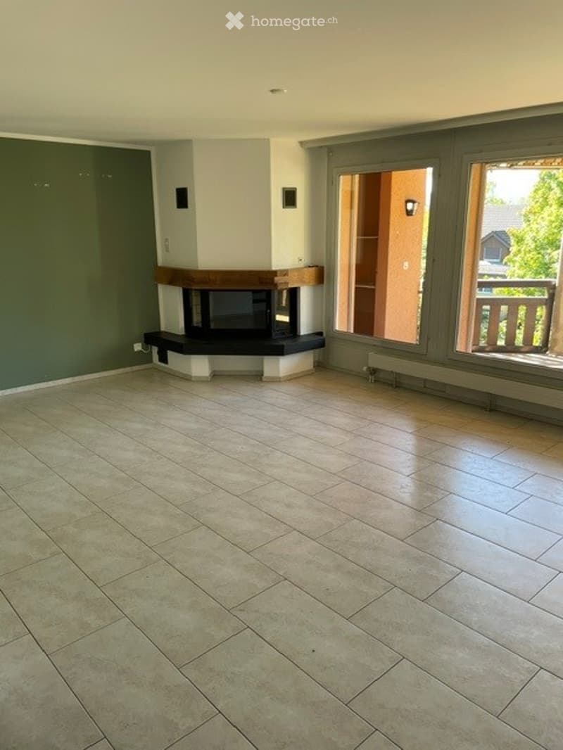 Empty room with tiled floor, fireplace, large windows, and balcony access.