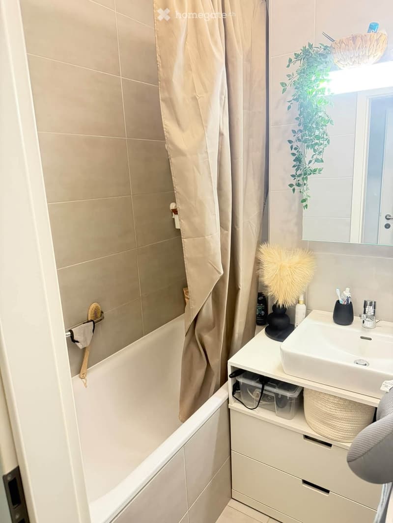 Modern bathroom with a bathtub, sink, mirror, and various toiletries neatly arranged on a vanity.