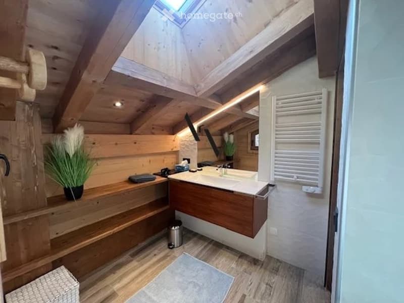Cozy wooden bathroom with a skylight, sink, mirror, and decorative flower arrangement on a wooden shelf.