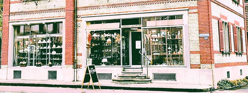 brick building, glass windows, display shelves, signboard, steps, sidewalk
