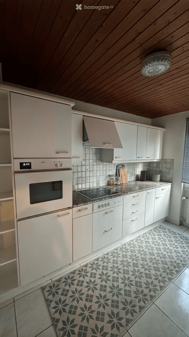 Modern kitchen with white cabinets, stainless steel appliances, granite countertop, and patterned tile floor.