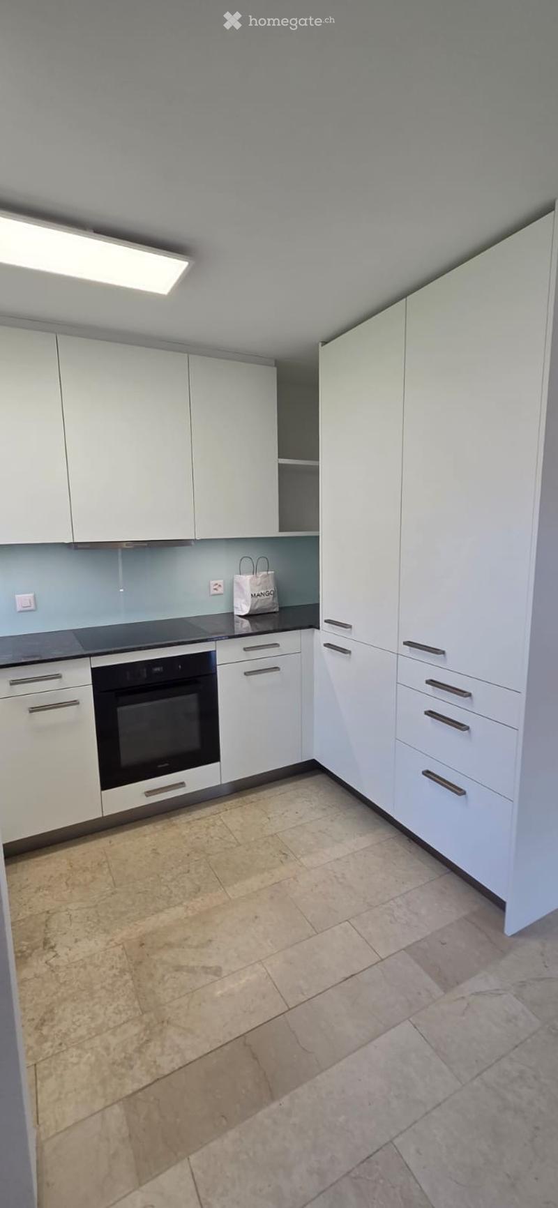 Modern kitchen with white cabinets, a built-in oven, and tiled flooring.