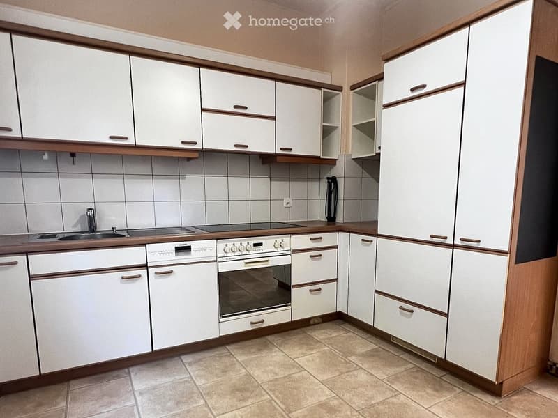 Modern kitchen with white cabinets, wooden trim, and tiled walls. Features a sink, faucet, oven, and dishwasher.
