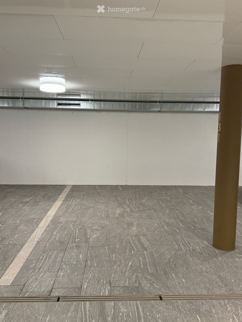 Empty hallway with grey marble flooring, white walls, and a glass ceiling with a single light fixture.