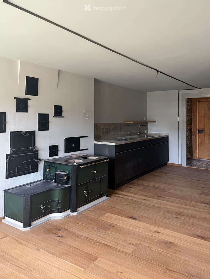 Modern kitchen with wooden flooring, a green vintage-style stove, a sink, and dark cabinets.