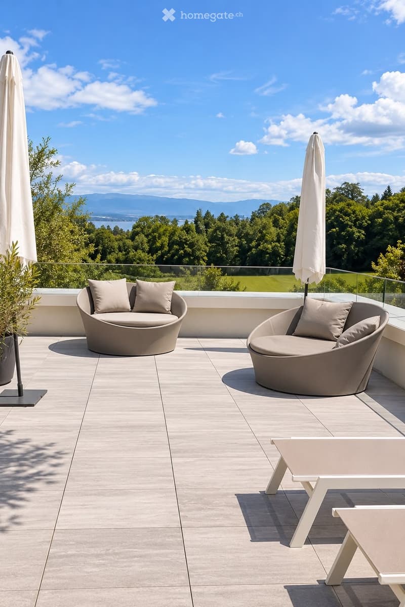 Modern balcony with two curved sofas, a small table, and two umbrellas, overlooking a scenic landscape with trees and mountains.
