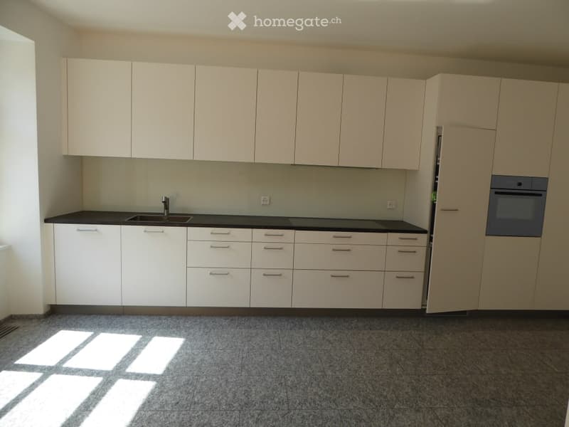 Modern kitchen with white cabinets, black countertops, and a built-in oven. Features a sink with a faucet and ample storage space.