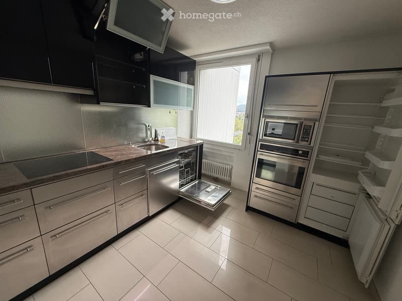 Modern kitchen with stainless steel appliances, granite countertop, and large window letting in natural light.